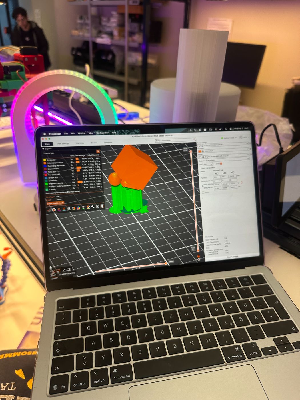 Laptop with a 3D model next to a 3D printer